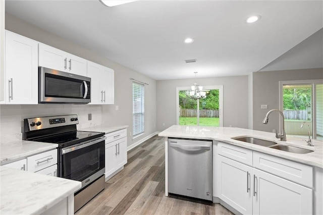 4625 Pine Blvd, Orange Beach, AL 36561 - kitchen with appliances with stainless steel finishes, a sink, white cabinetry, light wood-type flooring, and a chandelier
