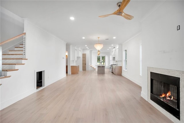 unfurnished living room with crown molding, light hardwood / wood-style flooring, and ceiling fan