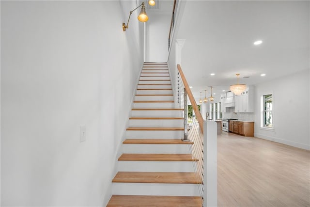 stairs featuring hardwood / wood-style floors and a notable chandelier