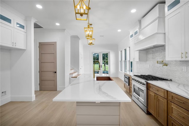 kitchen featuring white cabinetry, hanging light fixtures, a center island, and stainless steel stove