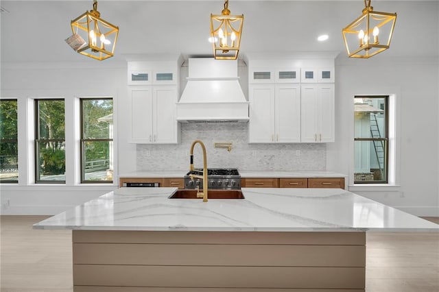 kitchen with custom exhaust hood, white cabinets, and decorative light fixtures