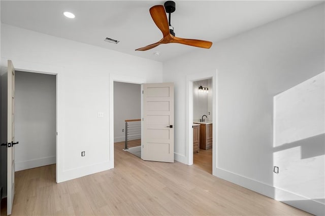 unfurnished bedroom with ceiling fan, light wood-type flooring, and ensuite bath