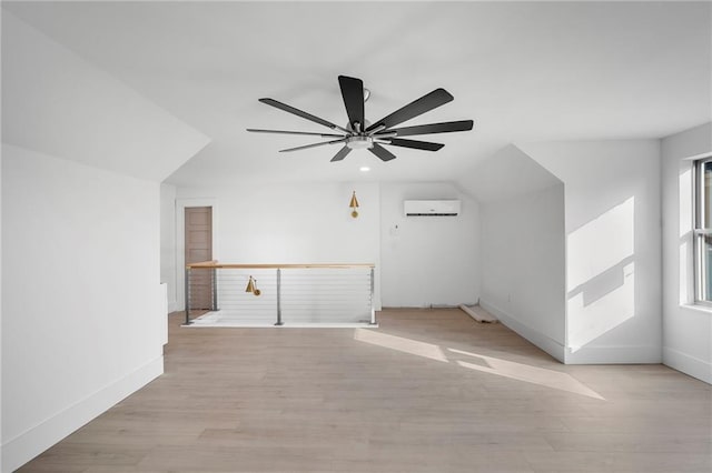 bonus room featuring light hardwood / wood-style floors, a wall mounted air conditioner, and ceiling fan