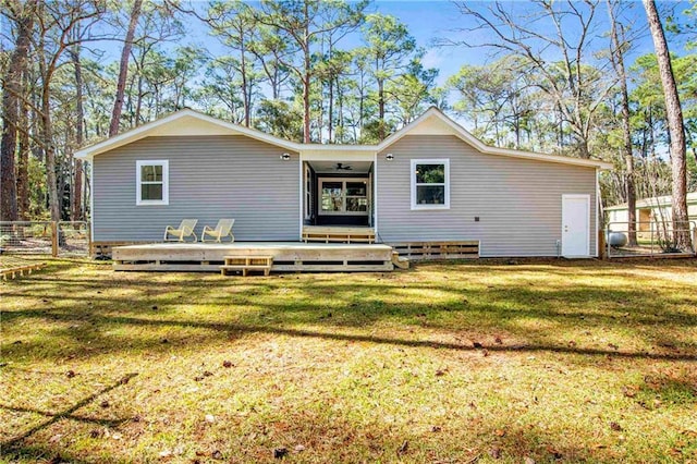 rear view of house featuring a deck, a lawn, and fence