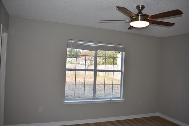 empty room with a textured ceiling, plenty of natural light, and dark wood-type flooring