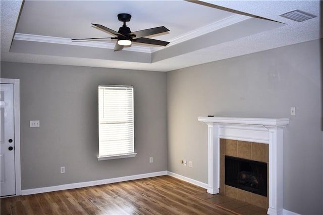 unfurnished living room featuring wood-type flooring, crown molding, and a tray ceiling