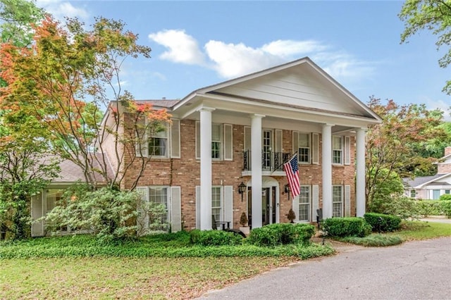 neoclassical home featuring a porch and brick siding