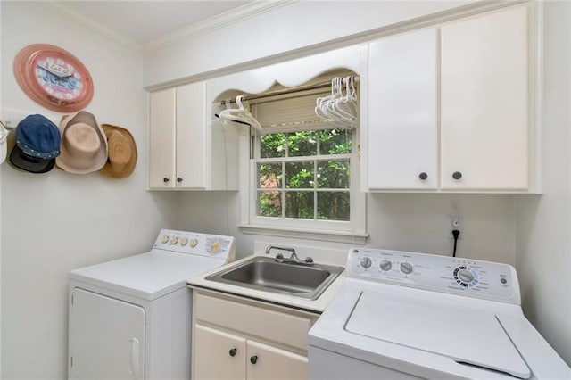clothes washing area featuring cabinet space, washer and clothes dryer, crown molding, and a sink