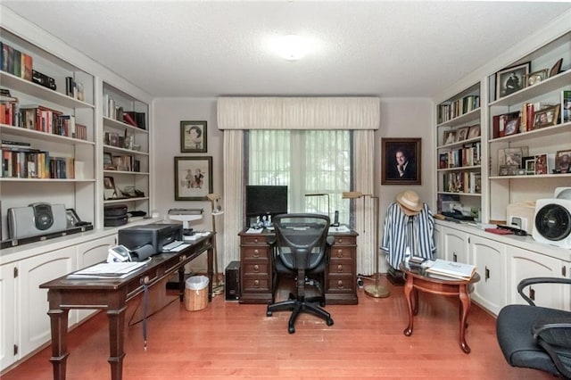 office area with built in features, a textured ceiling, and light wood finished floors