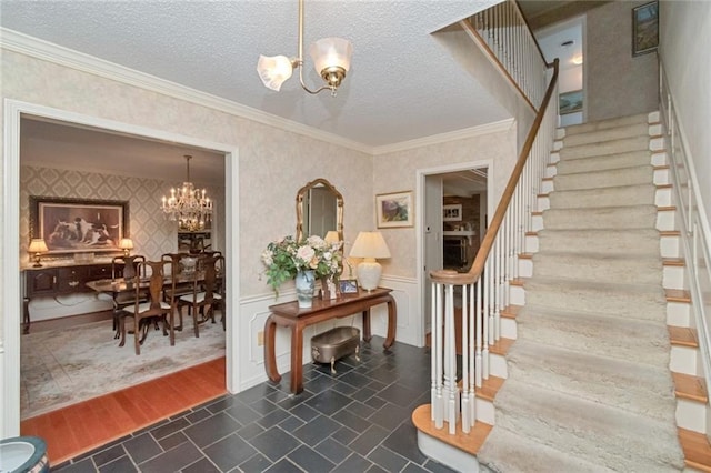 stairway with wallpapered walls, an inviting chandelier, a textured ceiling, and ornamental molding