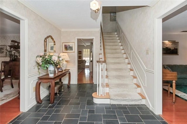 staircase with wainscoting, wallpapered walls, and ornamental molding