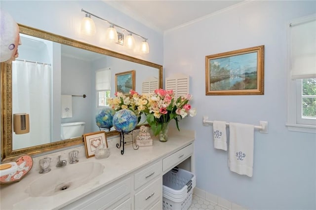 bathroom with toilet, baseboards, vanity, and crown molding