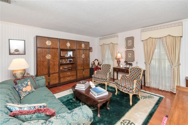 living area with wood finished floors, a textured ceiling, and crown molding