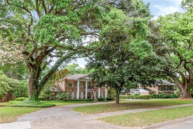 neoclassical home with aphalt driveway, a front yard, and brick siding