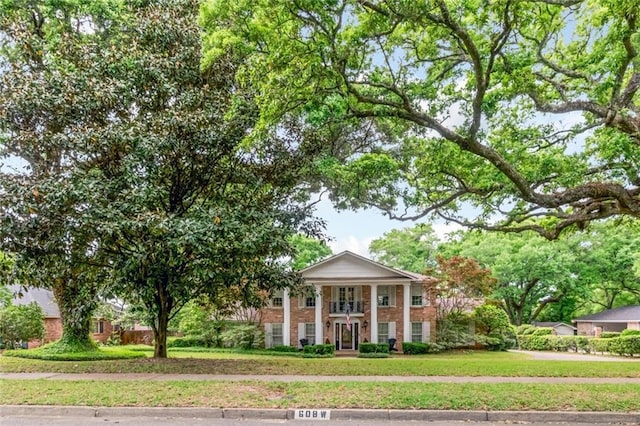 greek revival inspired property featuring brick siding and a front lawn