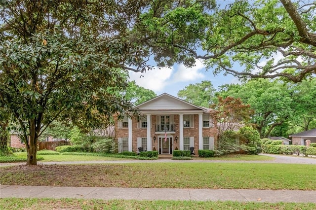 neoclassical / greek revival house with a front lawn and brick siding