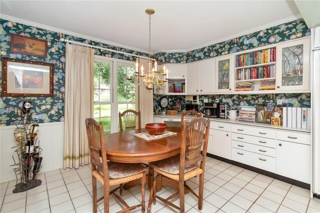 dining space with wainscoting, ornamental molding, a notable chandelier, and wallpapered walls