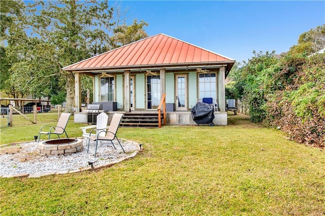 rear view of house with an outdoor structure, a fire pit, and a lawn