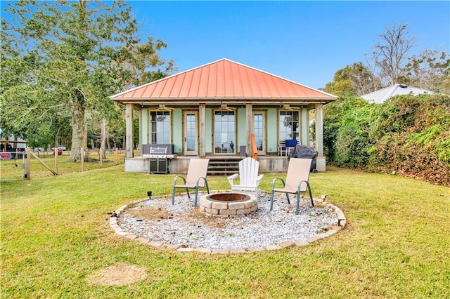 rear view of house featuring a yard, an outbuilding, and an outdoor fire pit