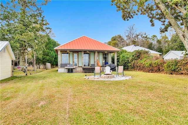 back of house featuring a yard and a fire pit