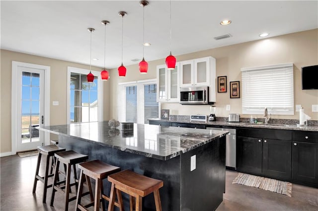 kitchen featuring sink, a breakfast bar area, white cabinetry, a center island, and appliances with stainless steel finishes