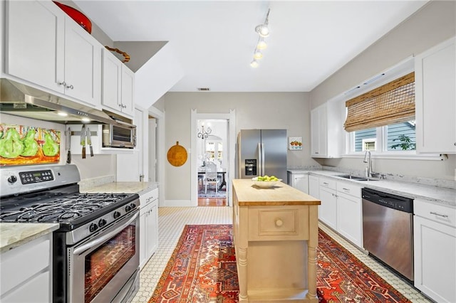 159 Roberts St, Mobile, AL 36604 - kitchen with stainless steel appliances, under cabinet range hood, butcher block counters, white cabinets, and track lighting