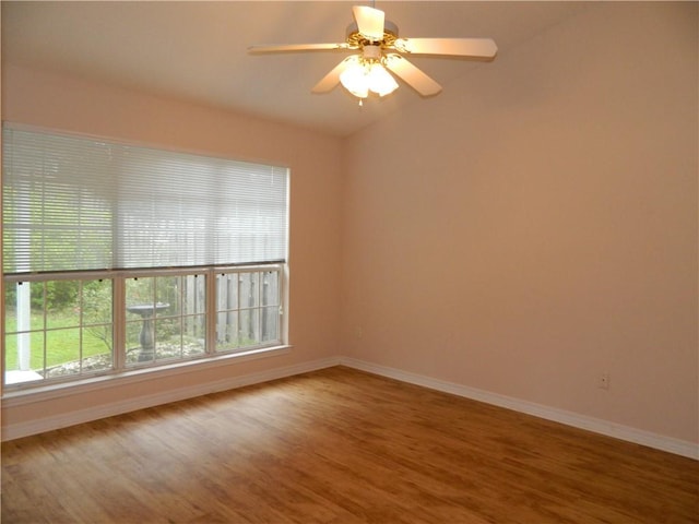 empty room featuring vaulted ceiling, ceiling fan, wood-type flooring, and a healthy amount of sunlight