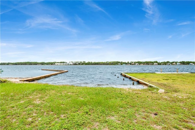 dock area with a water view and a lawn