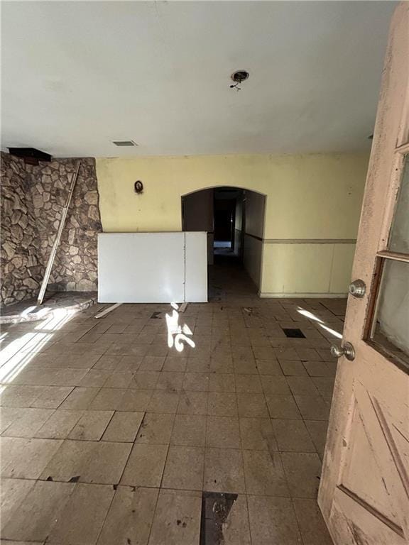 empty room featuring arched walkways and visible vents