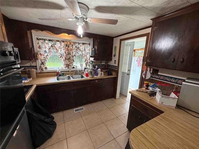 15162 Randolph Foster Rd, Wilmer, AL 36587 - kitchen with dark brown cabinetry, a ceiling fan, light countertops, light tile patterned floors, and black oven