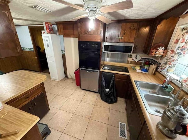 15162 Randolph Foster Rd, Wilmer, AL 36587 - kitchen with black appliances, light countertops, light tile patterned floors, ceiling fan, and wood walls