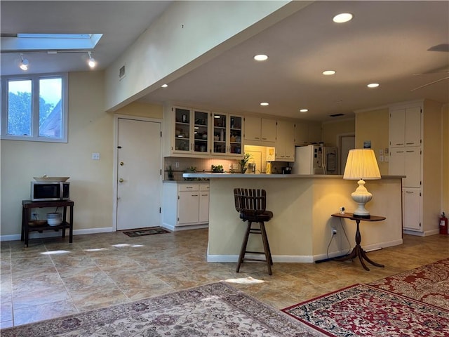 5721 Long Meadow Rd, Mobile, AL 36609 - kitchen with refrigerator, a skylight, glass insert cabinets, recessed lighting, and a breakfast bar