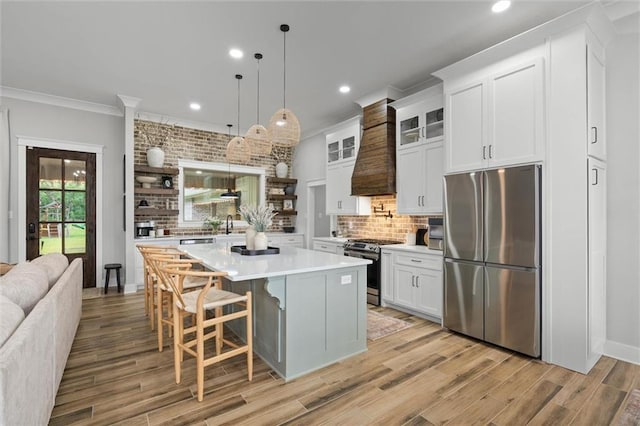 kitchen featuring custom exhaust hood, crown molding, backsplash, light countertops, and appliances with stainless steel finishes