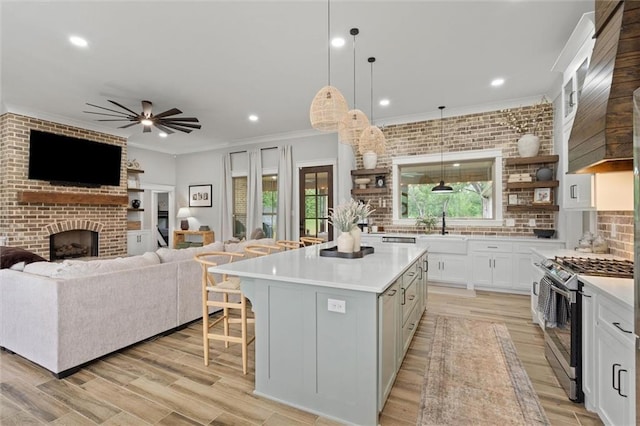 kitchen featuring a breakfast bar, a sink, a fireplace, stainless steel gas stove, and crown molding
