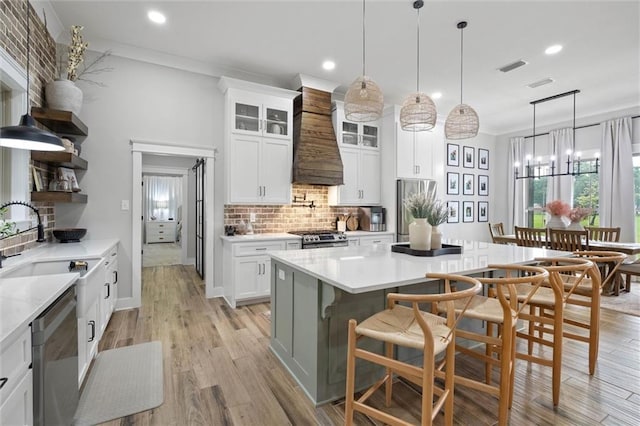 kitchen with a sink, stainless steel appliances, tasteful backsplash, custom range hood, and recessed lighting