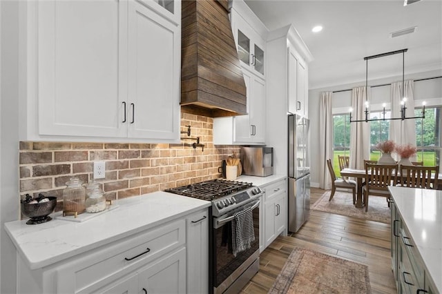 kitchen with white cabinets, appliances with stainless steel finishes, glass insert cabinets, and decorative light fixtures