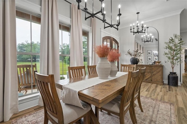 dining space featuring a chandelier, light wood-style flooring, and crown molding