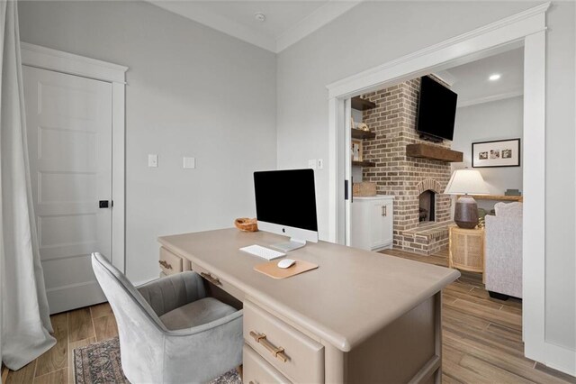 office space featuring ornamental molding, a brick fireplace, and light wood-type flooring