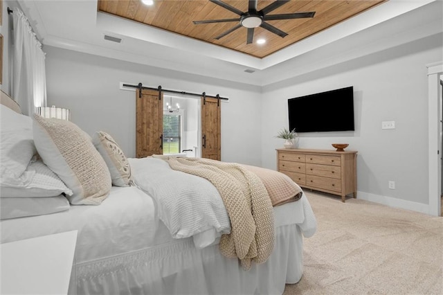 bedroom with a tray ceiling, a barn door, baseboards, light colored carpet, and recessed lighting
