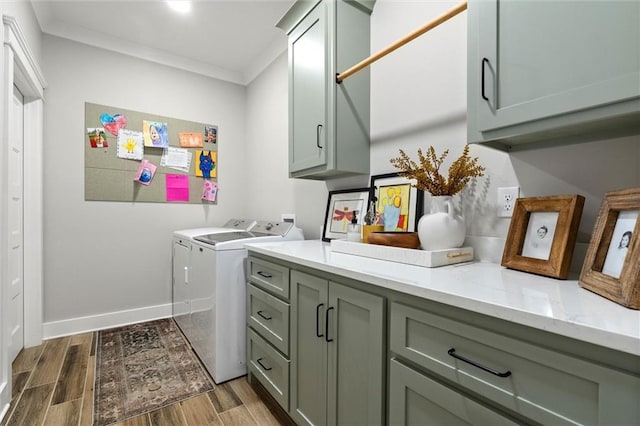 clothes washing area featuring baseboards, ornamental molding, light wood finished floors, washer and clothes dryer, and cabinet space