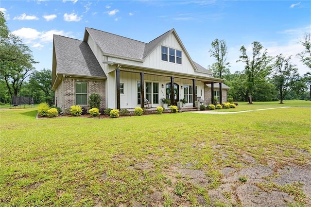 exterior space featuring a porch, roof with shingles, a front lawn, and board and batten siding