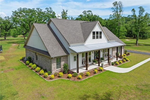 rear view of house with a lawn, board and batten siding, a standing seam roof, covered porch, and roof with shingles