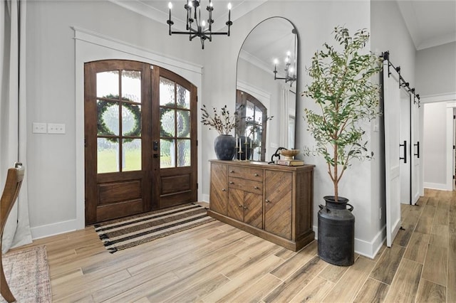 foyer with ornamental molding, a notable chandelier, french doors, and baseboards