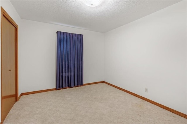 spare room featuring light colored carpet and a textured ceiling