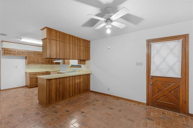 kitchen featuring ceiling fan, sink, and kitchen peninsula