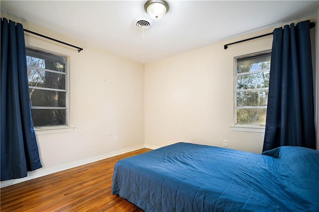 bedroom with visible vents, baseboards, and wood finished floors