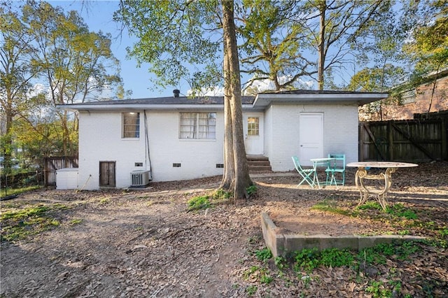 back of property featuring entry steps, crawl space, fence, central air condition unit, and brick siding