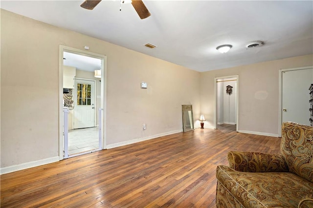 living area with wood-type flooring, visible vents, and baseboards