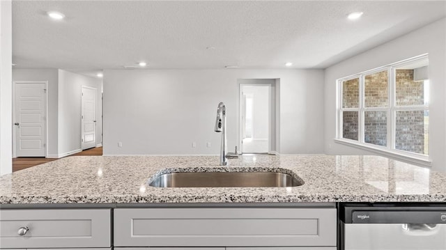 8616 Brooklyn Ct, Semmes, AL 36575 - kitchen with stainless steel dishwasher, light stone countertops, a textured ceiling, recessed lighting, and wood finished floors