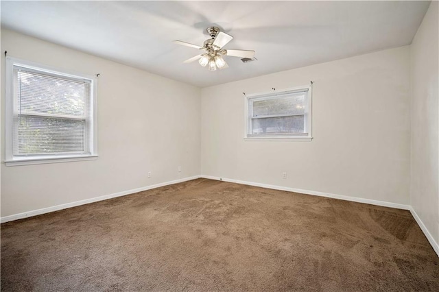 empty room with ceiling fan and dark colored carpet